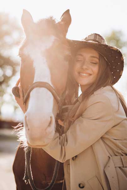 Young happy woman with horse at ranch